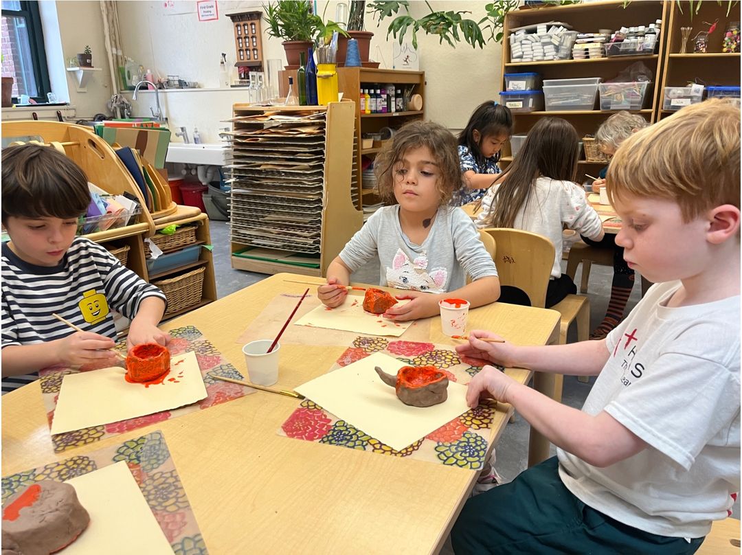 Young children shaping and painting clay pots during a Reggio-inspired arts activity