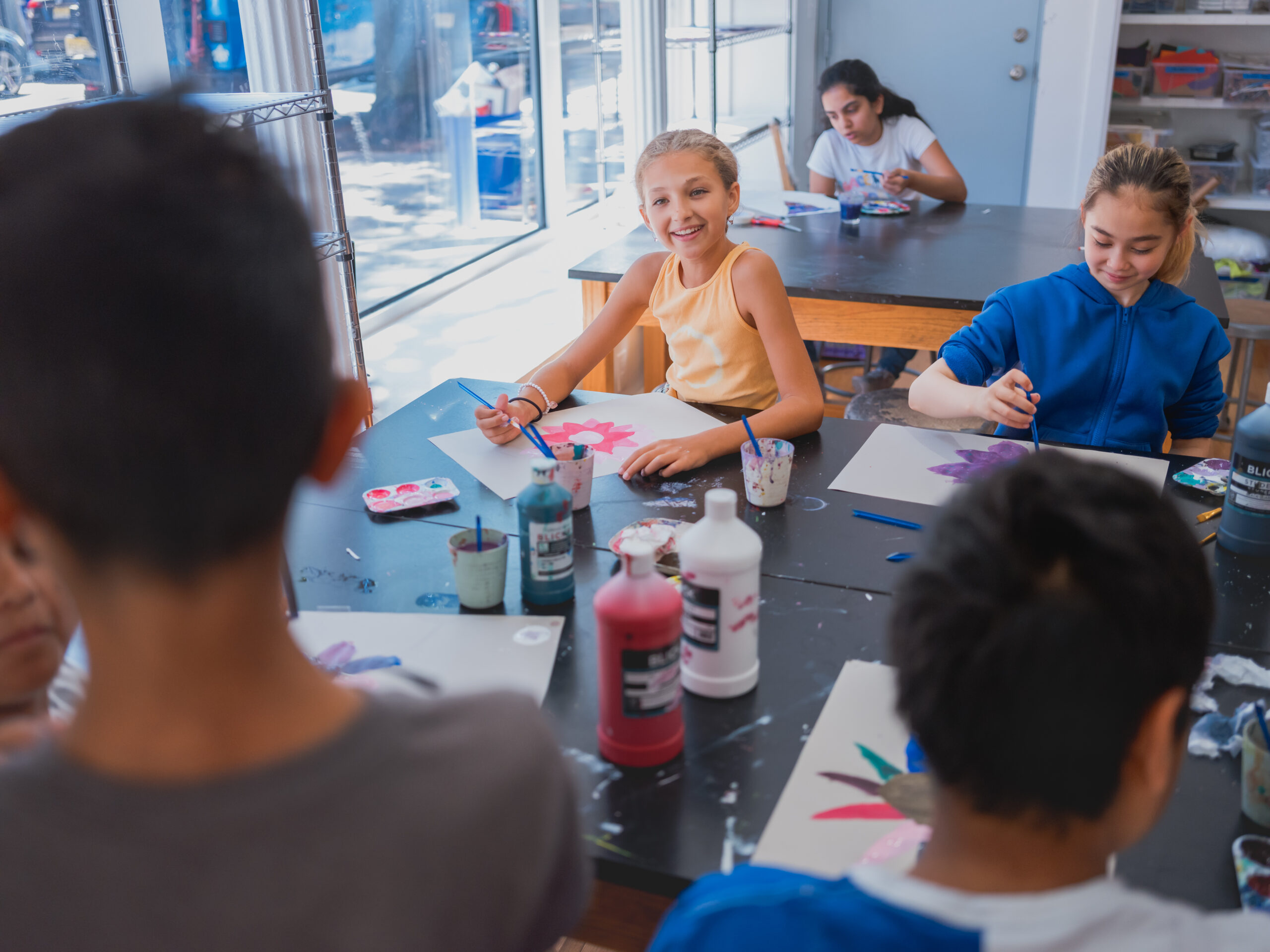 Hudson School students painting watercolors together in a sunlit art room