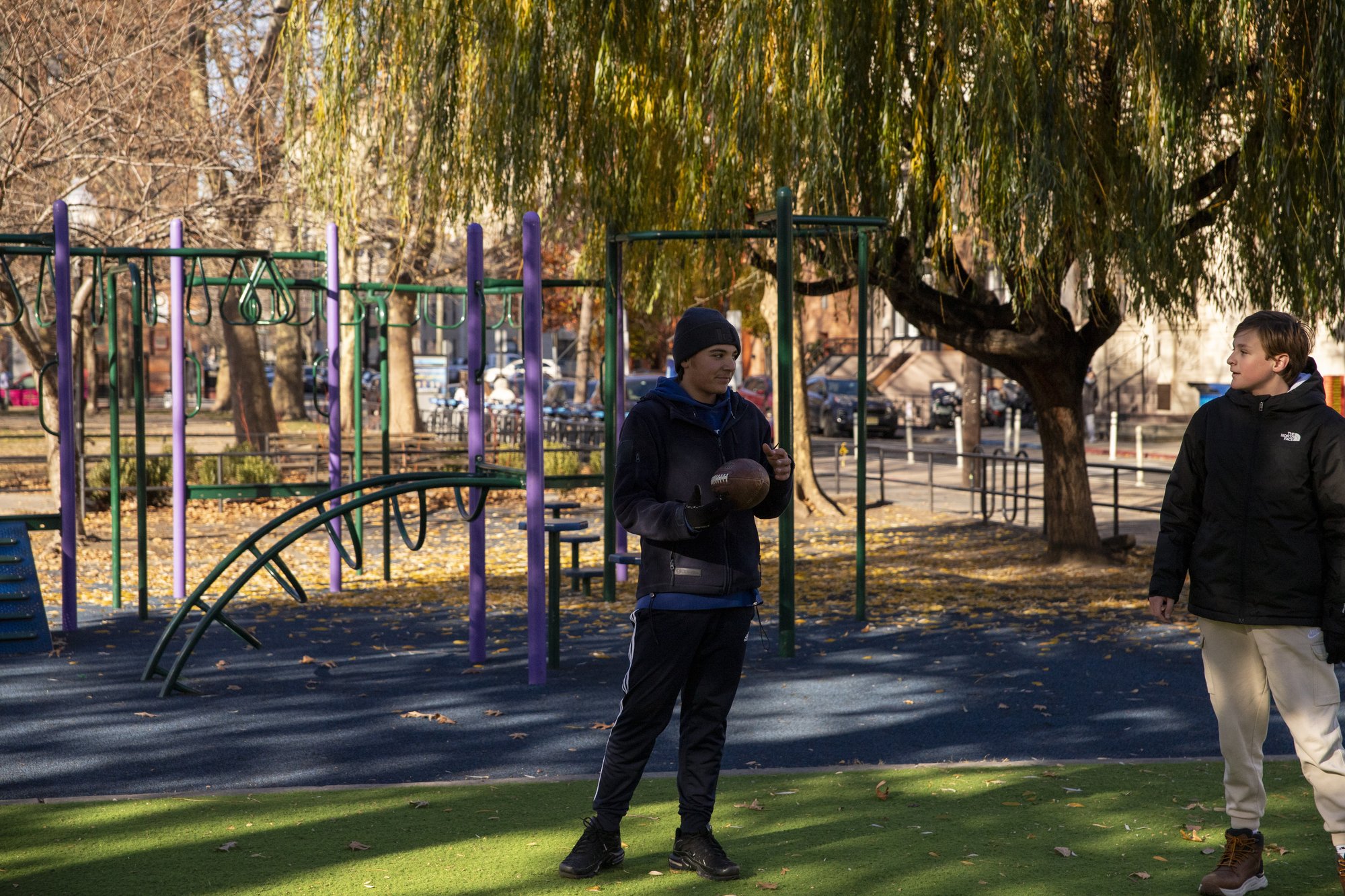 Student jumping near tree in urban park