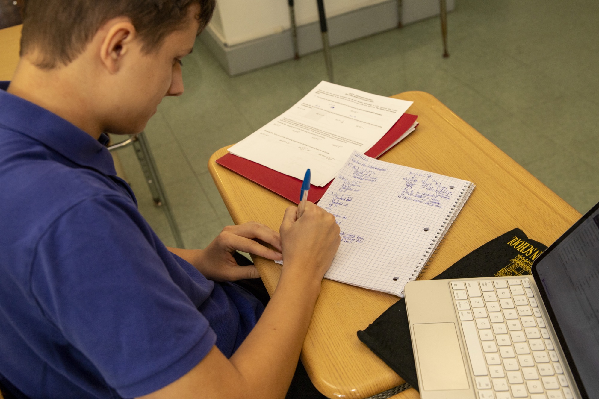 Close-up of hands writing in a notebook on a desk