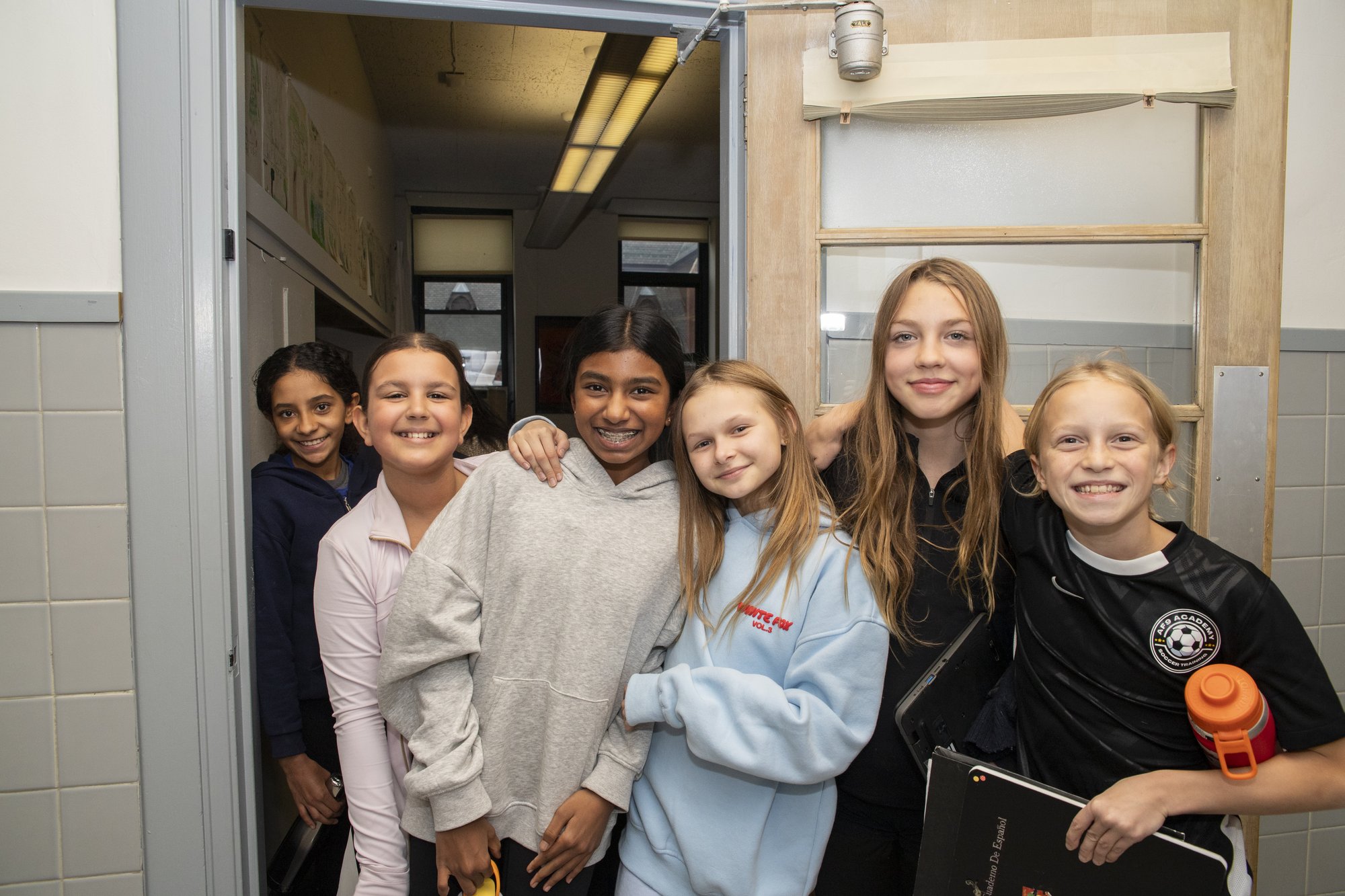 Two students posing smiling in hallway