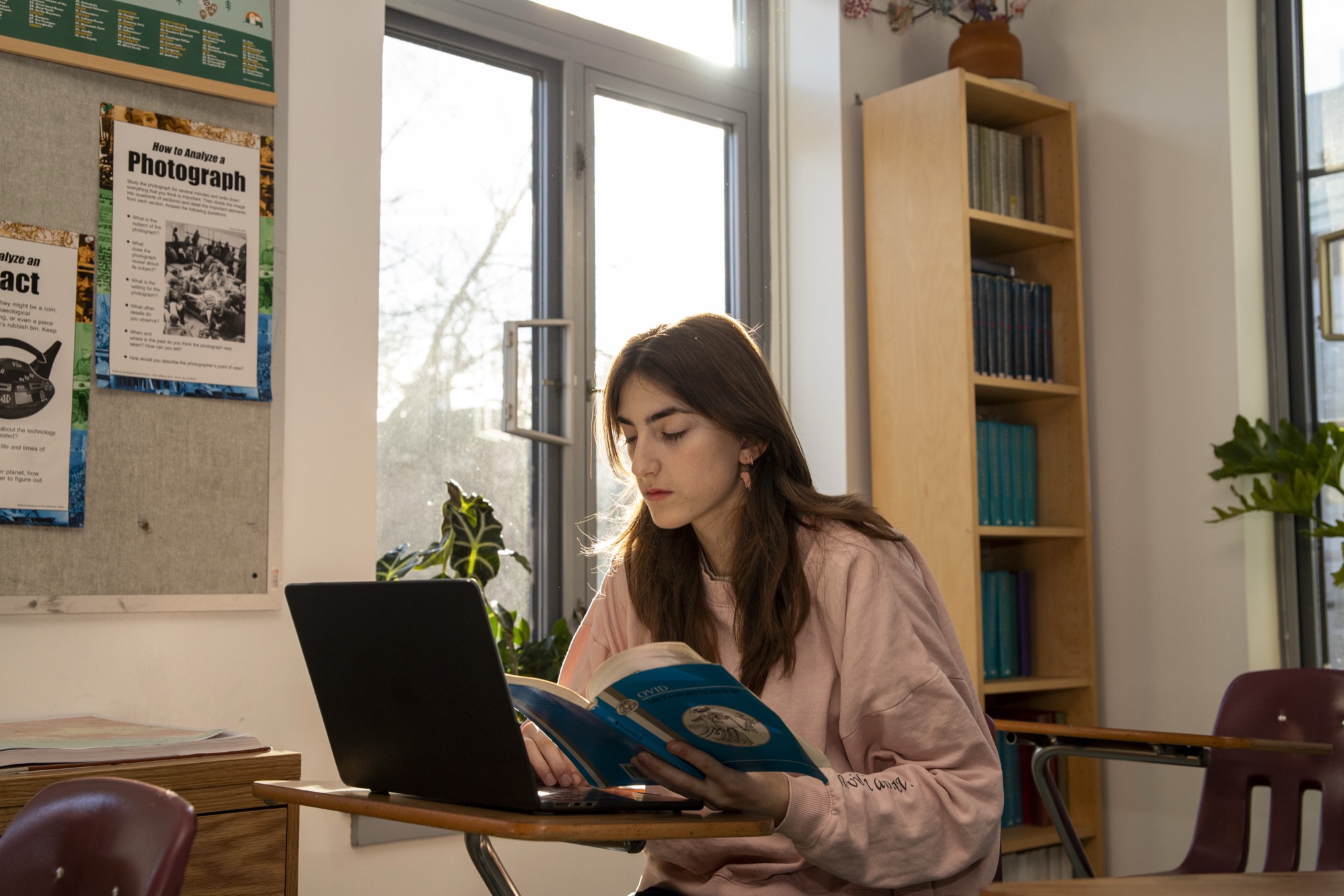 A female student reading a book in a sunny Hudson School classroom