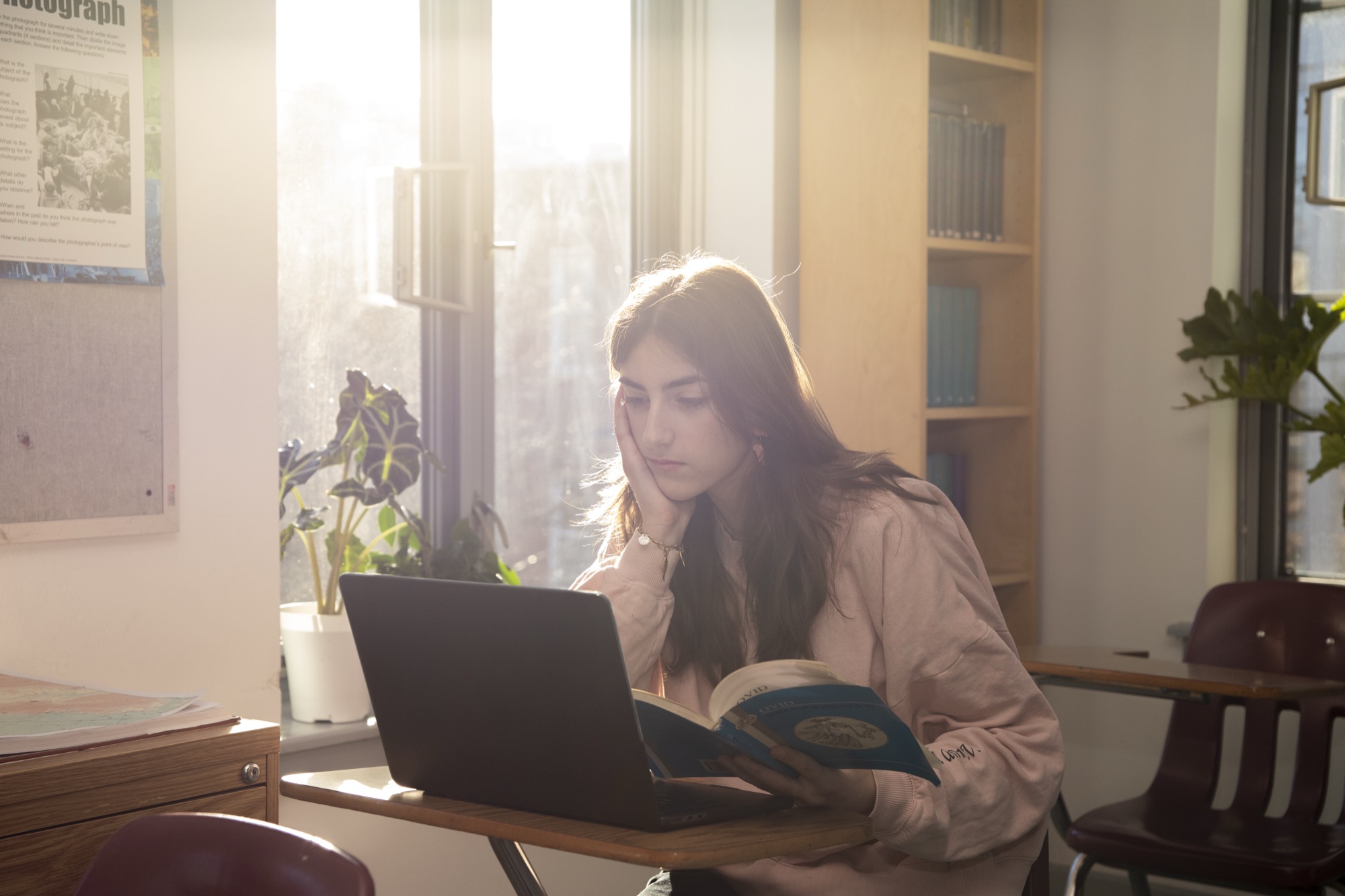 Female Hudson School student at a laptop in a warm sunlit wood-furnished room