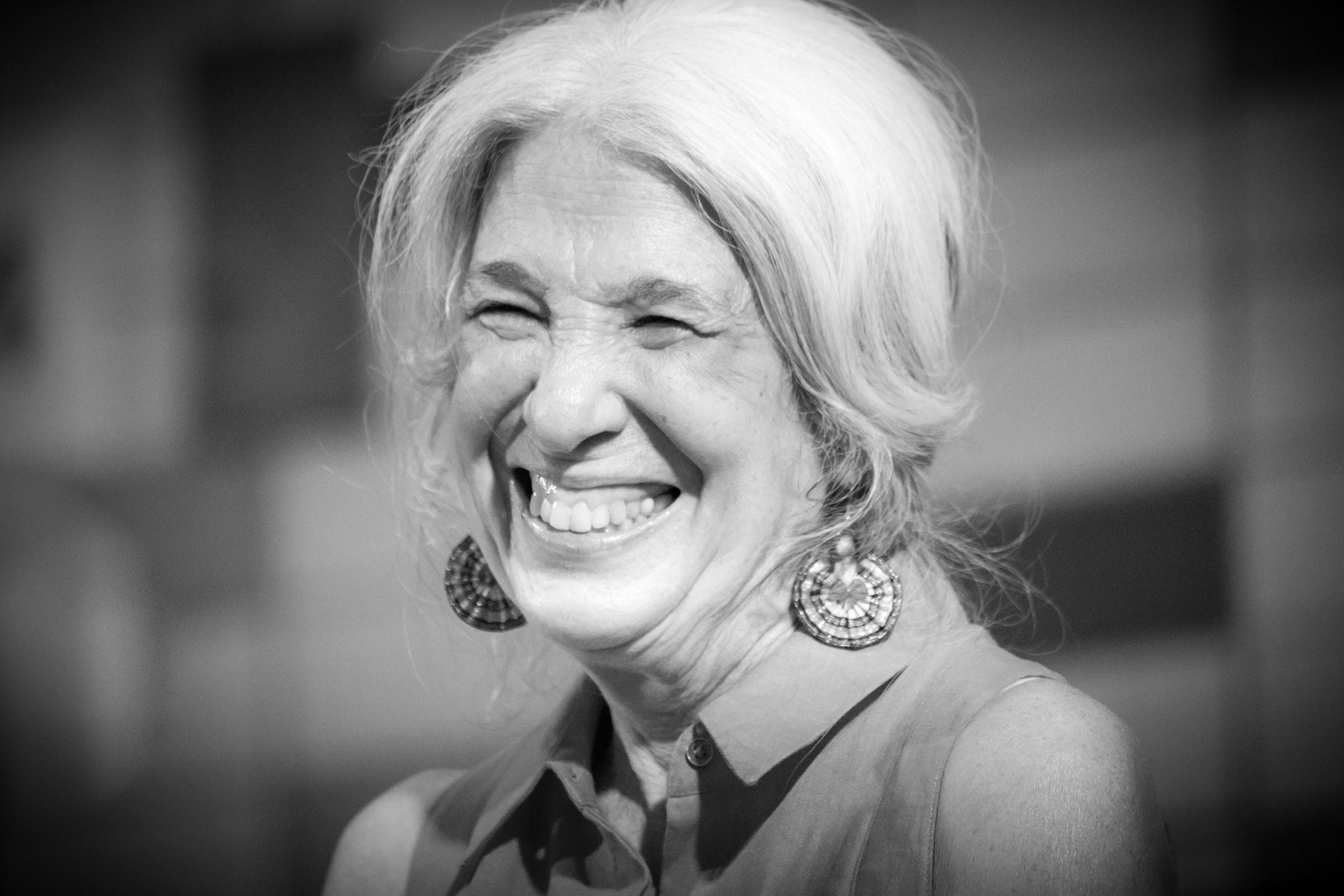 Hudson School founder Suellen Newman laughing, in a black-and-white portrait.